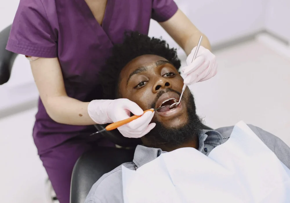 young-african-american-man-guy-visiting-dentist-s-office-prevention-oral-cavity-man-famale-doctor-while-checkup-teeth-min